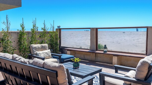 A patio with outdoor furniture, a potted plant, and a view of the beach. - 1205O Spanish Beach Bungalow Retreat (Oxnard)