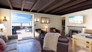 A living room with a fireplace, a television, and a view of the outdoors. - 1205O Spanish Beach Bungalow Retreat (Oxnard)
