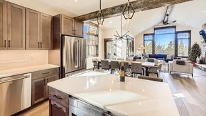 A modern kitchen with a large island, stainless steel appliances, and a rustic ceiling. - Modern Retreat | Views | Shuttle Stop (Breckenridge)