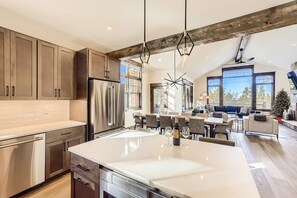 A modern kitchen with a large island, stainless steel appliances, and a rustic ceiling.