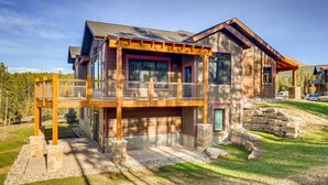 A two-story house with a balcony, stone foundation, and a view of a forested area. - Modern Retreat | Views | Shuttle Stop (Breckenridge)