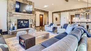 A spacious living room with a stone fireplace, a flat-screen TV, and a large sofa. - Modern Retreat | Views | Shuttle Stop (Breckenridge)