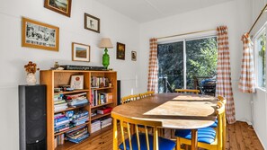 A dining area with a wooden table, blue chairs, a bookshelf, and a window with curtains.