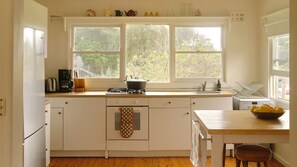 A kitchen with a window, a stove, a sink, and a bowl of lemons on the counter.