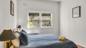 A bedroom with a bed, a window, a radiator, and a lamp.