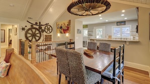 Un espace repas comprenant une table et des chaises en bois, un lustre et des éléments décoratifs sur les murs, notamment des engrenages et un tableau.