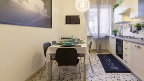 Kompakti keittiö, jossa on ruokailutila, seinälle asennettu televisio ja keittiösaareke, jossa on pesuallas.