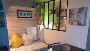 Une chambre à coucher avec un lit, une table sur laquelle se trouve un bol, une chaise, une fenêtre et une étagère fixée au mur avec une plante.