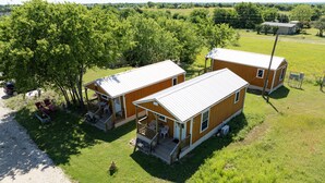 Eine kleine, eingeschossige Holzhütte mit einer Veranda und einem überdachten Sitzbereich im Freien.