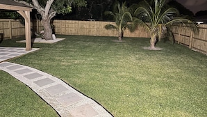 A backyard with a wooden deck, a palm tree, and a wooden fence.