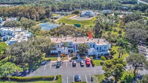 Surrounded by a well-manicured lawn and a parking area, this building offers a serene suburban setting with a tennis court nearby.