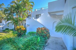 Stylish building with a geometric design, featuring a balcony and lush green surroundings.