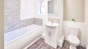 Ein modernes Badezimmer mit Badewanne, Waschbecken und Toilette.
