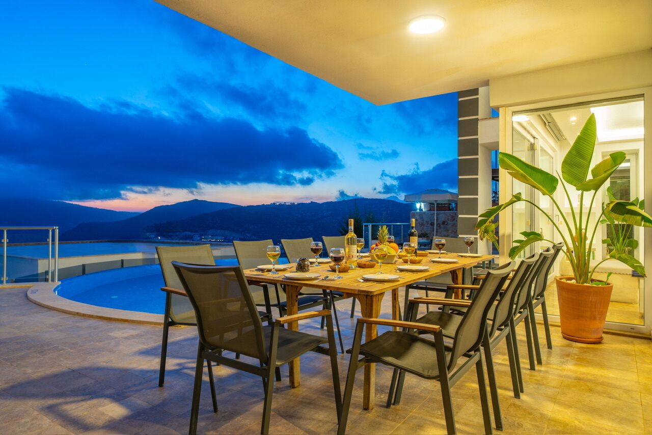 Un comedor con piscina y vistas a las montañas al atardecer.
