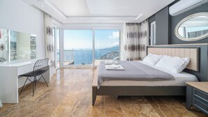 Une chambre moderne avec un grand lit, un bureau et une vue sur la mer.