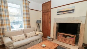 Ein Wohnzimmer mit einer Couch, einem Couchtisch, einem Kamin und einem Fernseher.