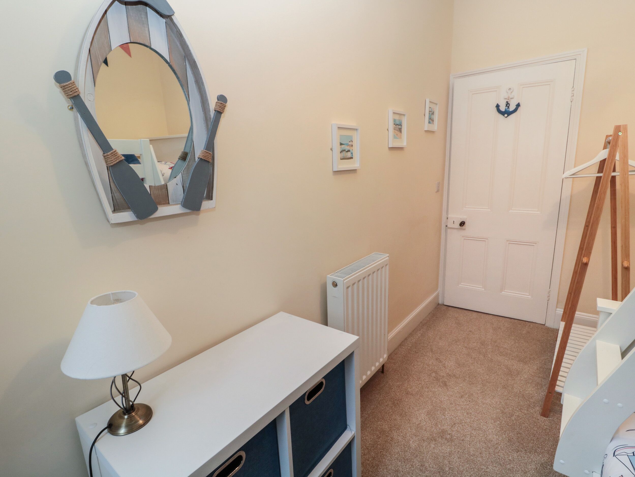 A hallway with a white door, a radiator, a mirror, and a lamp.