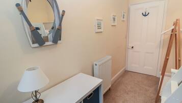 A hallway with a white door, a radiator, a mirror, and a lamp.