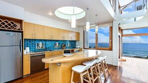 Una cocina moderna con una isla central, armarios de madera y vistas al océano.