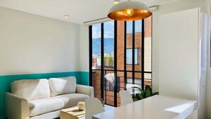 Una sala de estar moderna con un sofá blanco, una mesa de comedor blanca y una lámpara colgante.