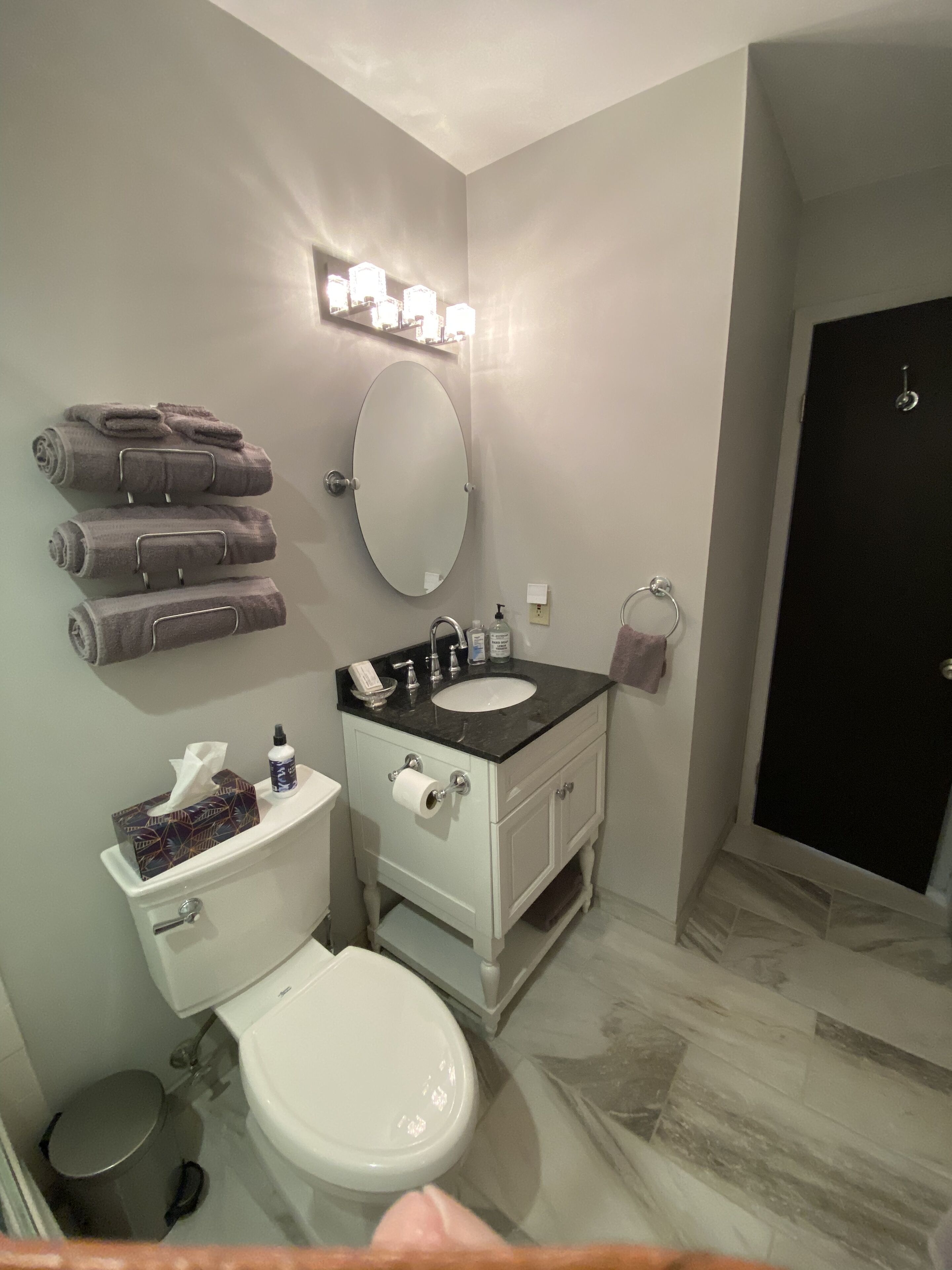 Baño con inodoro, lavamanos, espejo y toallero.