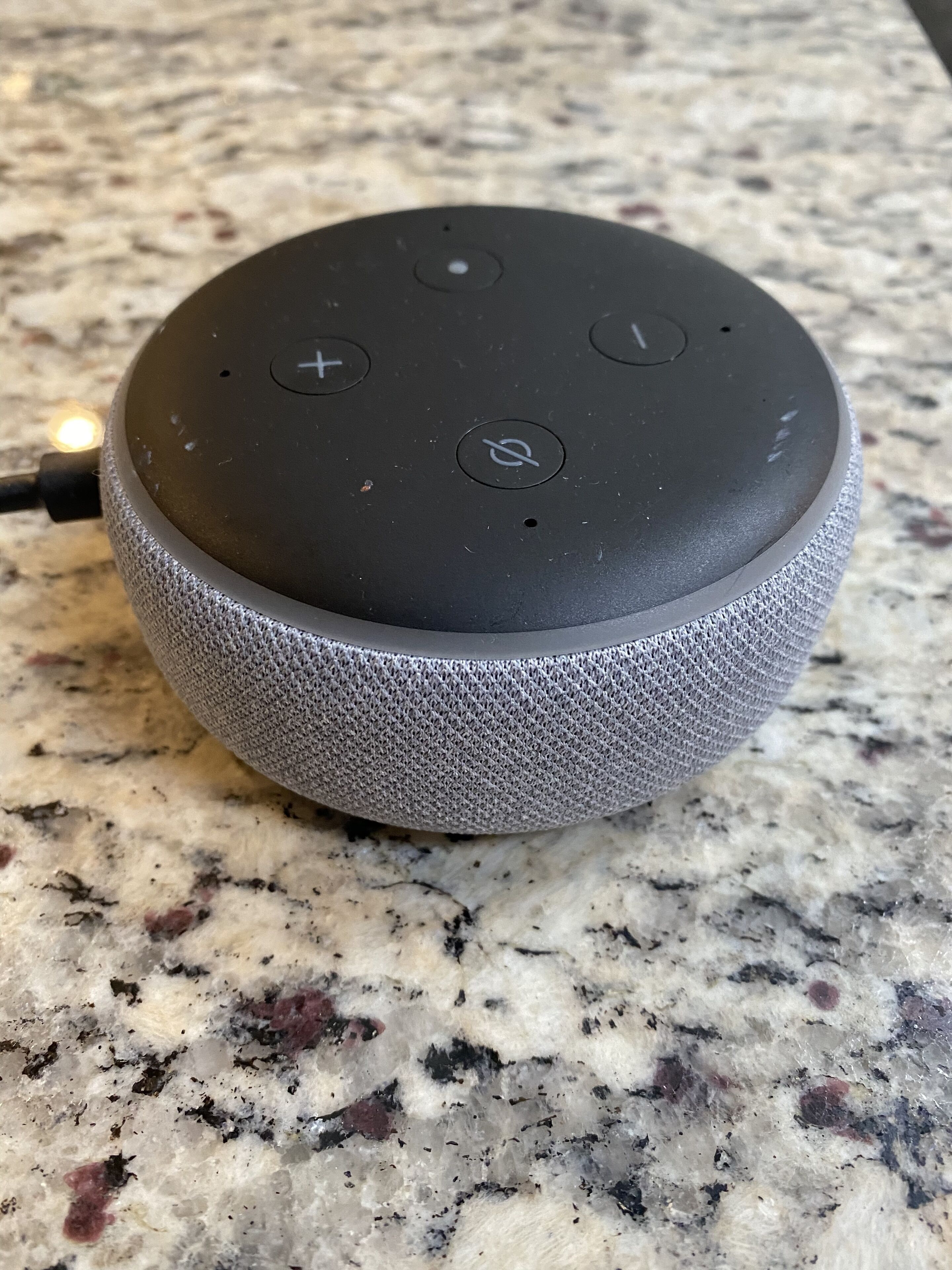 A smart speaker on a granite countertop.