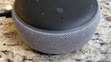 A smart speaker on a granite countertop.