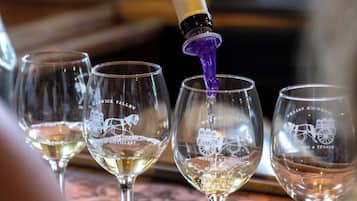 Four wine glasses with a horse and carriage logo, one glass being filled with a purple liquid.