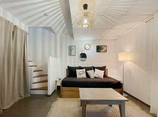 Un dormitorio con cama, mesita de noche, lámpara, reloj y una obra de arte colgada en la pared.