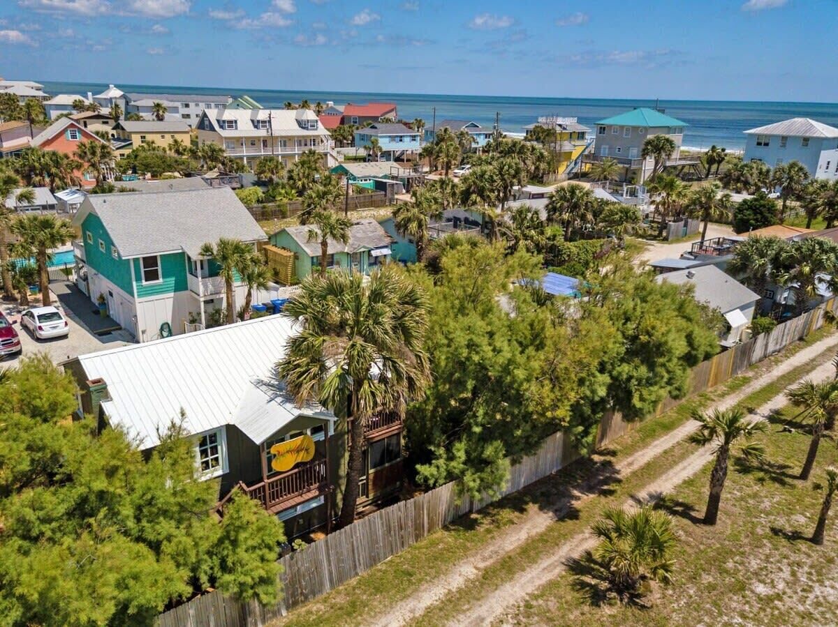 A coastal residential area with houses, a beach, and a clear sky.