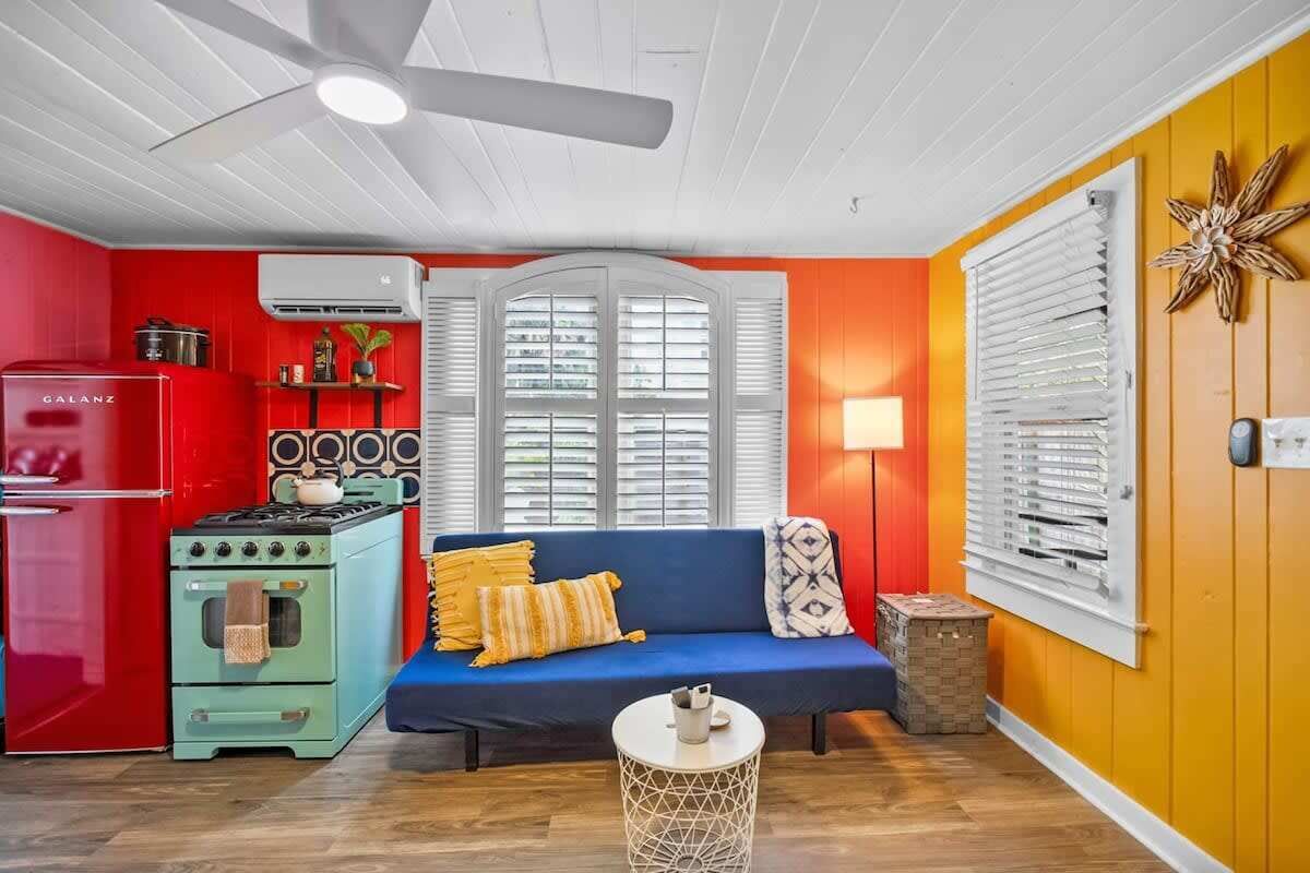 A compact living space with a kitchenette, a blue sofa, and a ceiling fan.