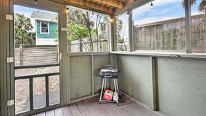 Un espacio al aire libre techado con una parrilla, techo de madera y vistas a una casa.