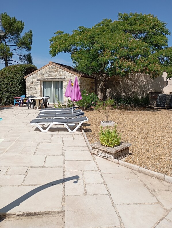 A stone patio with outdoor furniture, a small table, and two purple umbrellas. - Les Cigales Grospierres, Lorbeer Studio near Vallon-pont-d'Arc, shared pool (Grospierres)