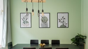 Un comedor con una mesa larga, seis sillas y tres láminas botánicas enmarcadas en la pared.