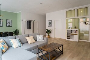 Relax in this stylish living room with a grey sofa, wooden coffee table, and bookshelf, offering a peaceful view of the outside.