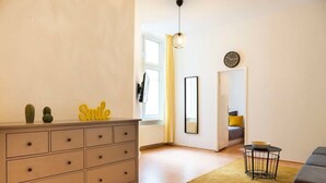 A modern living room with a grey dresser, a yellow rug, and a black clock on the wall.