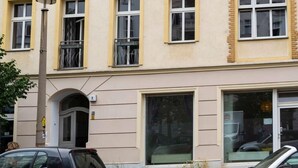 Un edificio de varios pisos con ventanas de marco amarillo, un balcón visible y una entrada de garaje.
