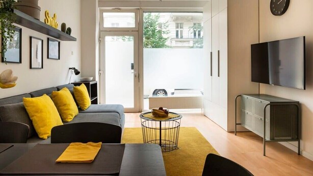 Una sala de estar moderna con sofá, mesa de centro y mueble para televisión.