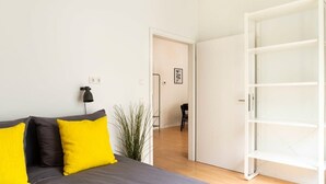 Un dormitorio con una cama, un armario blanco y una puerta que da a otra habitación.