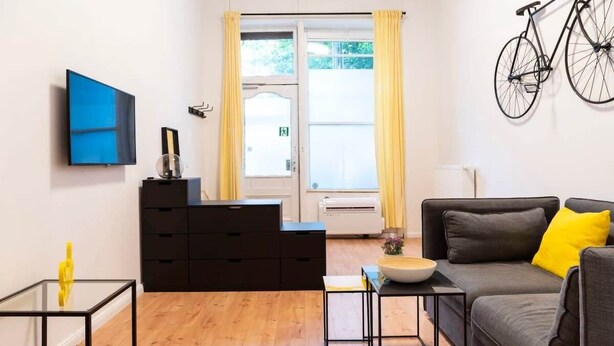 A modern living room with a sofa, coffee table, and a TV mounted on the wall.