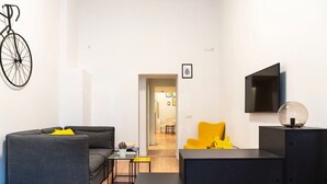 A modern living room with a sofa, a yellow chair, a coffee table, and a TV.
