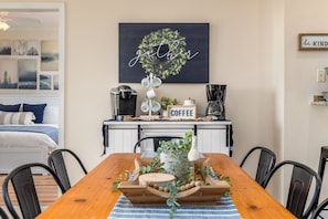 Un coin repas chaleureux avec une table en bois, des chaises noires et un espace dédié au café.