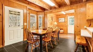 Un interior de madera con una mesa de comedor y sillas, un banco y un pequeño taburete.