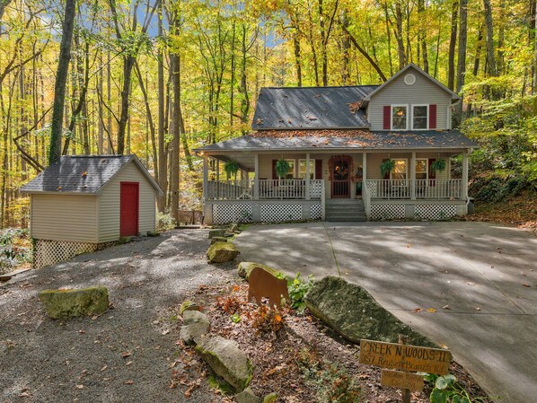 A two-story house with a porch, a small shed, and a driveway.