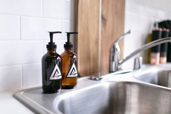 Deux bouteilles dotées de pompes noires, posées sur un plan de travail de cuisine en acier inoxydable.