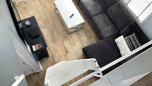 Una sala de estar moderna con un sofá gris, una mesa de centro blanca y una mesita auxiliar negra.