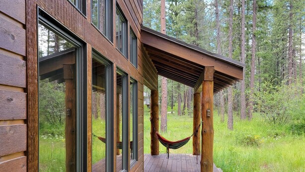 A wooden cabin with large windows, a hammock, and a deck overlooking a forest. - Triple J Cabin (Mazama)