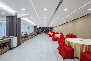 A conference room with rows of tables and chairs, a stage, and a buffet area. - Sports International Hotel (Kunshan)