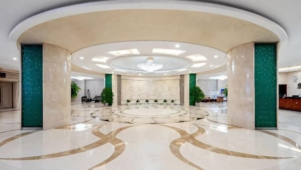 A spacious lobby with a circular seating area, a reception desk, and a chandelier. - Sports International Hotel (Kunshan)