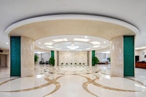 Un'ampia hall con una zona salotto circolare, una reception e un lampadario.